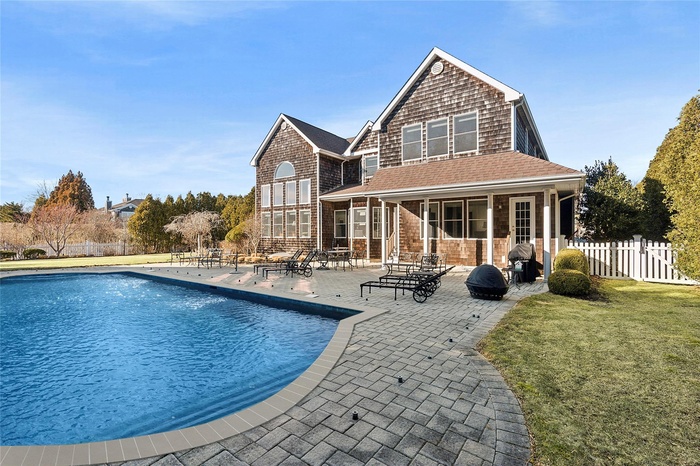 Rear view of house featuring a fenced in pool, fence, a lawn, and a patio