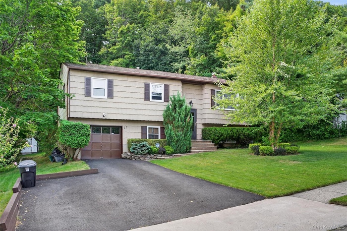 Bi-level home featuring asphalt driveway, a front yard, and an attached garage