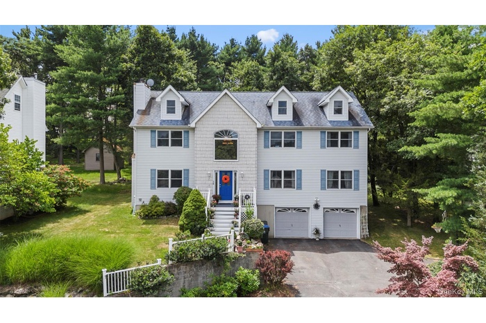 View of front of property featuring asphalt driveway, a chimney, a shingled roof, and a garage