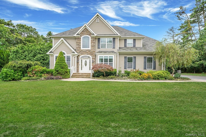 Traditional-style home with a front lawn, stone siding, and a shingled roof