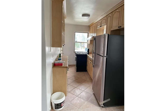 Kitchen with stainless steel appliances, light stone countertops, light tile patterned floors, and light brown cabinets