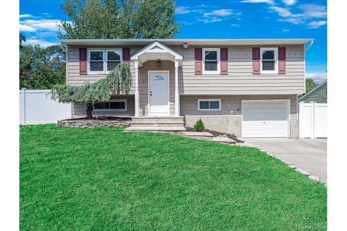 Raised ranch featuring concrete driveway and a garage