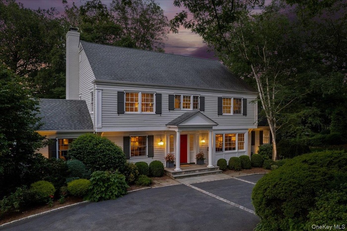 View of front of house featuring a porch, a chimney, and a shingled roof