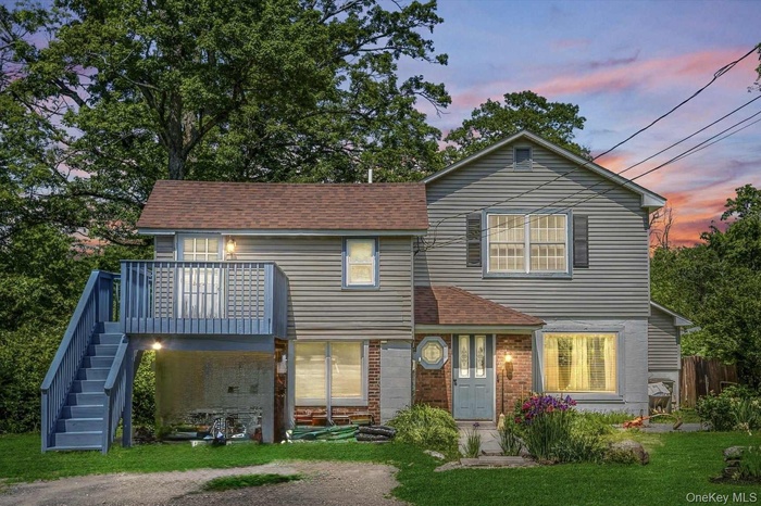 Rear view of property featuring stairs, a yard, roof with shingles, and a deck