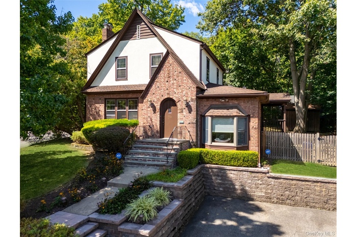 English style home featuring stucco siding, a chimney, and brick siding