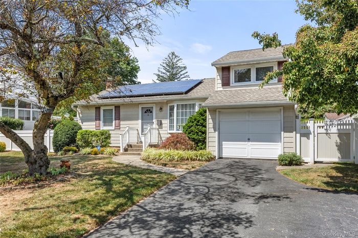 View of front of house featuring roof with shingles, asphalt driveway, roof mounted solar panels, a gate, and an attached garage