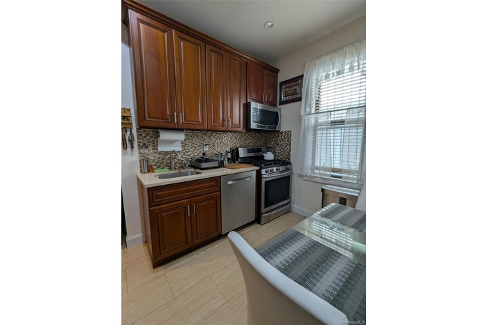 Kitchen with appliances with stainless steel finishes, backsplash, recessed lighting, light tile patterned flooring, and light stone countertops