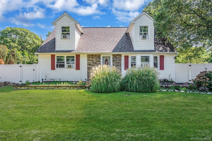 Cape cod-style house with a gate, roof with shingles, and stone siding