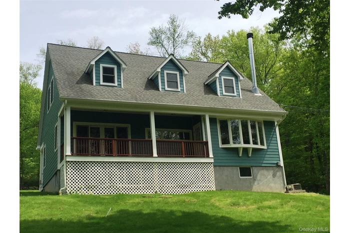 View of front of home with a front lawn, roof with shingles, and covered porch