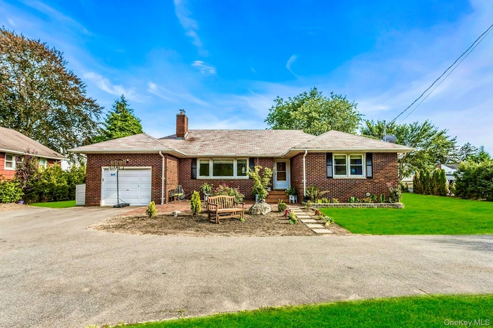 Single story home featuring an attached garage, asphalt driveway, brick siding, and a chimney