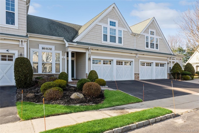 View of front of home with driveway, a garage, stone siding, and roof with shingles