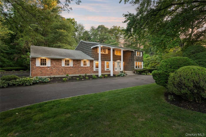 View of front of property with a front yard, a porch, brick siding, and view of scattered trees