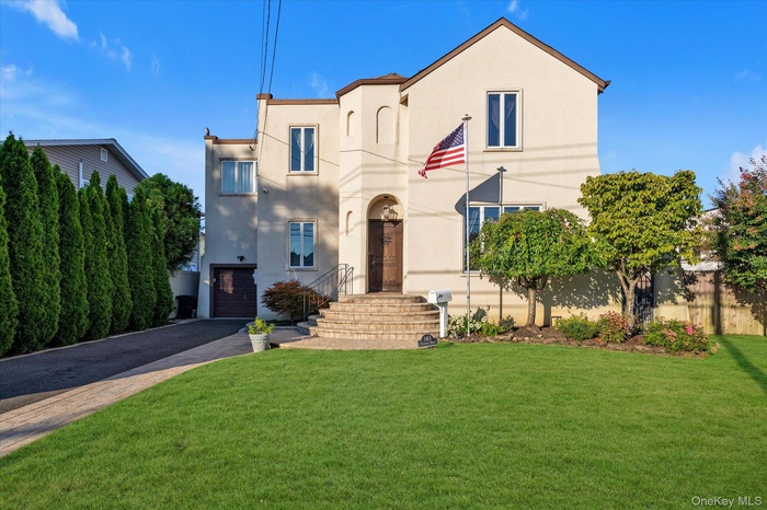 Mediterranean / spanish-style home featuring stucco siding, driveway, a front lawn, and a garage
