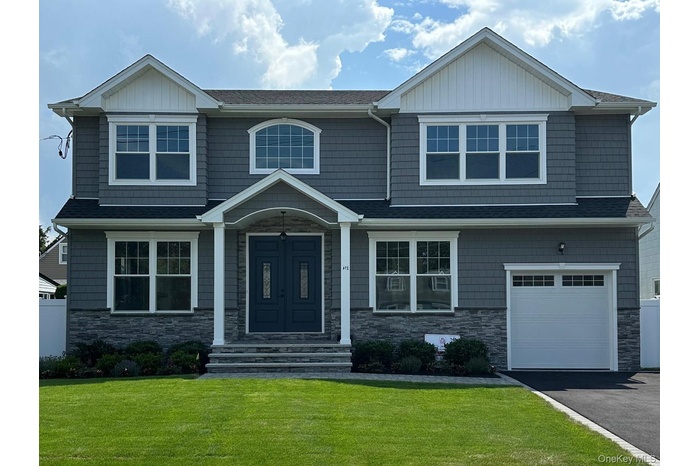 Craftsman inspired home with stone siding, a front lawn, a garage, and driveway
