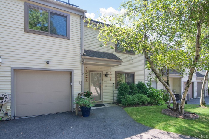 Traditional home featuring an attached garage, driveway, and a front lawn.