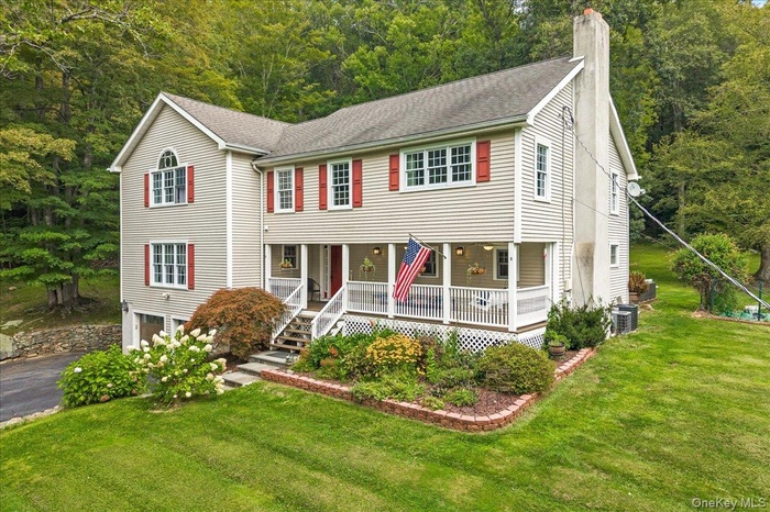 View of front of home featuring a chimney, covered porch, a front lawn, and roof with shingles