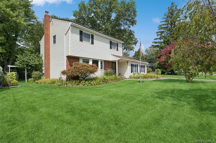 View of front of house featuring a front yard, a chimney, and brick siding