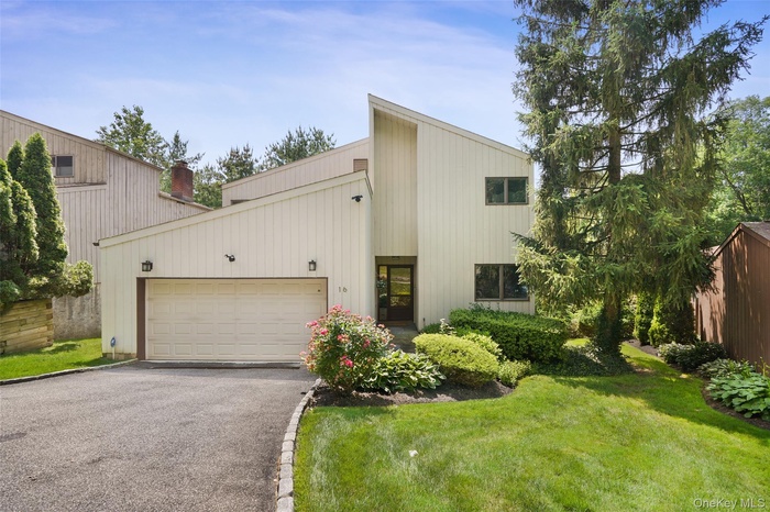 Contemporary inspired home with asphalt driveway, a garage, a front lawn, and a chimney