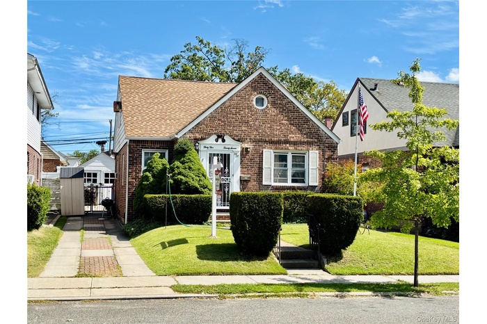 Tudor-style house featuring brick siding, roof with shingles, and a front yard