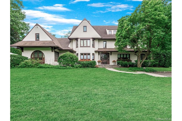 View of front of home featuring a front yard, stucco siding, a porch, and roof with shingles