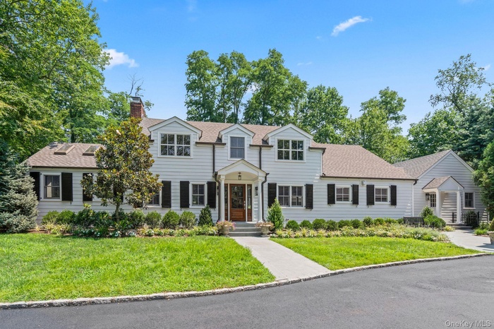 View of front of property featuring a chimney, a front yard, and a shingled roof