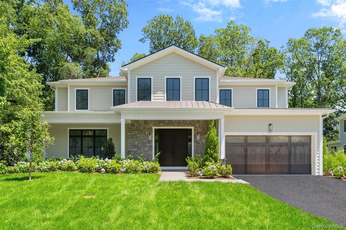 View of front facade with stone siding, a front lawn, a porch, asphalt driveway, and an attached garage