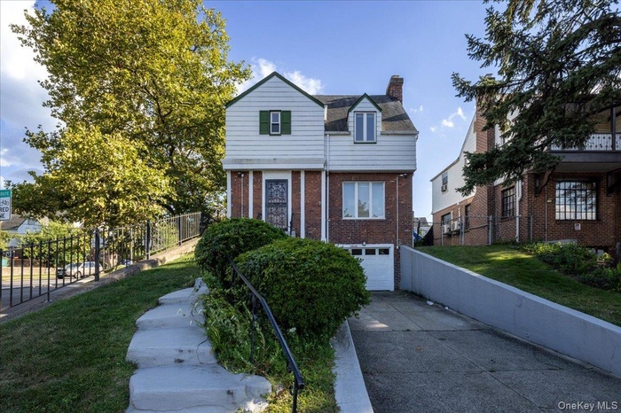 View of front of home featuring a chimney, concrete driveway, an attached garage, and brick siding