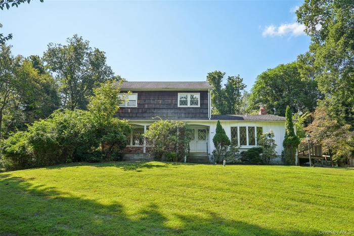 View of front of home featuring a front lawn, a chimney, and covered porch