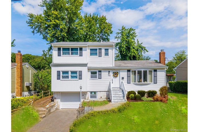 View of front of property featuring driveway, a garage, and a chimney