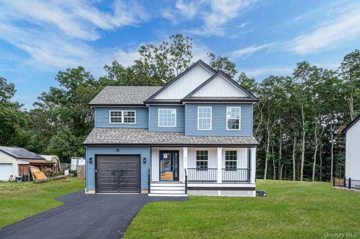 View of front of home with roof with shingles, a front lawn, a porch, and asphalt driveway