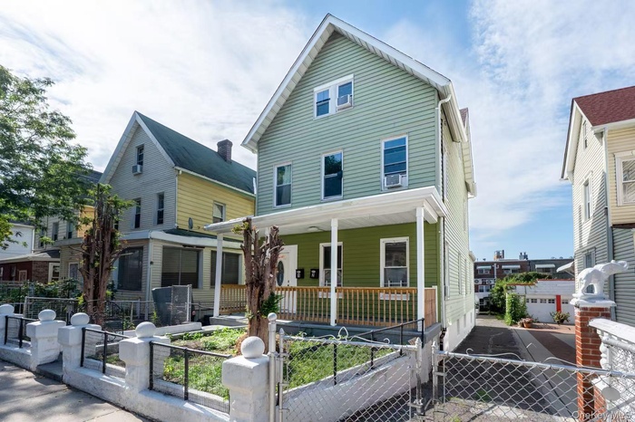 View of front of house with a porch, a fenced front yard, and a gate