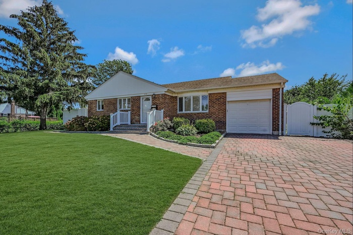 Ranch-style house featuring a gate, an attached garage, decorative driveway, and brick siding
