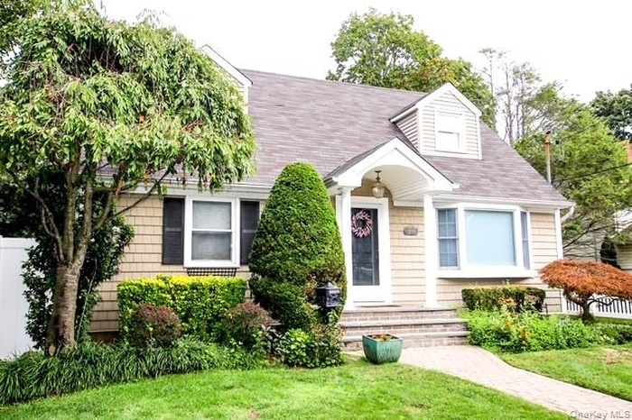 Cape cod-style house with a front lawn and a shingled roof