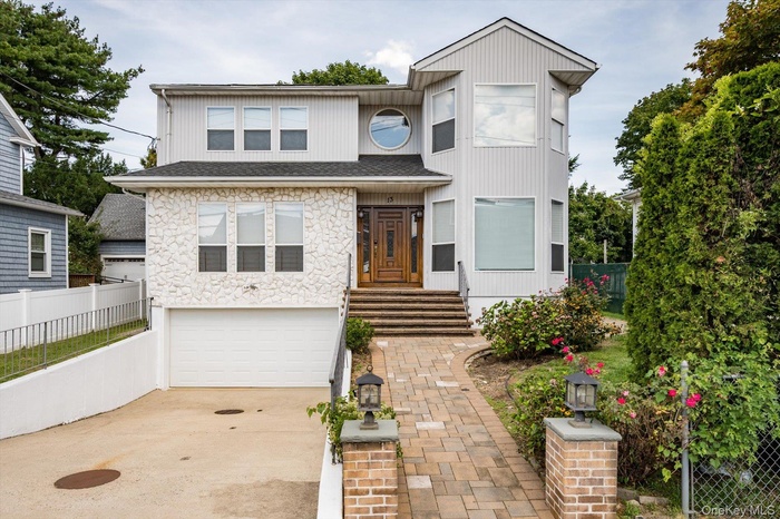 View of front facade featuring driveway, an attached garage, and stone siding