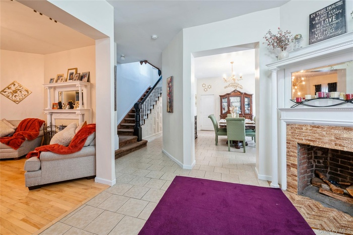 Living area with a fireplace with flush hearth, stairs, tile patterned flooring, and a chandelier