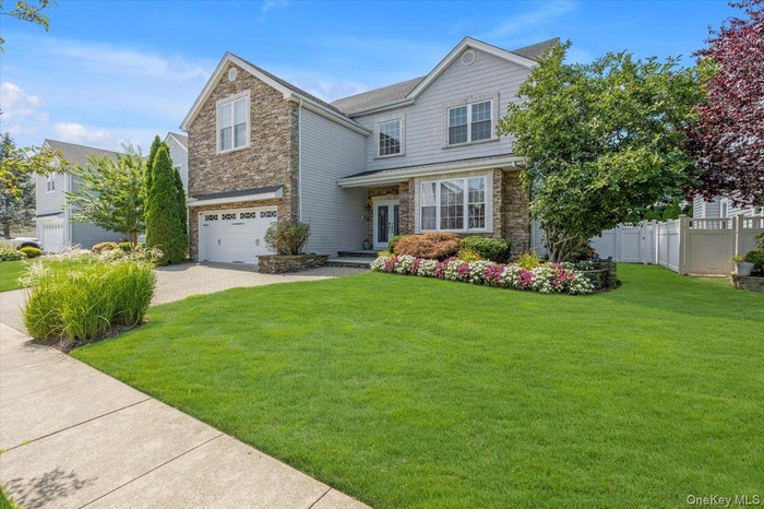 Traditional-style home featuring stone siding, decorative driveway, and an attached garage