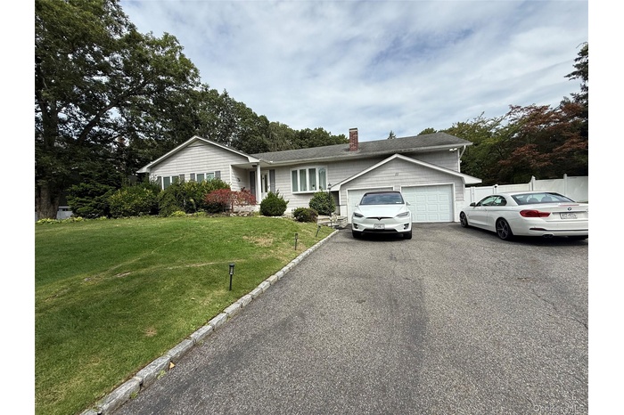 Single story home with asphalt driveway, a front yard, an attached garage, and a chimney