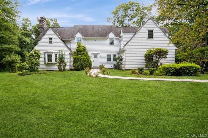 Rear view of house with a chimney and a lawn