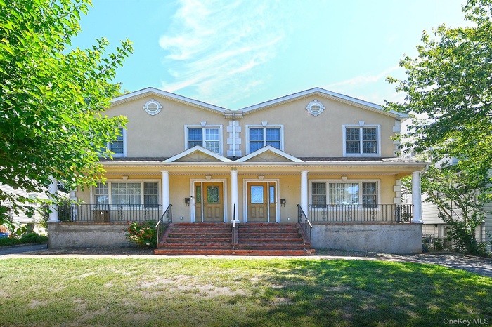 View of front of house with stucco siding, a porch, and a front lawn