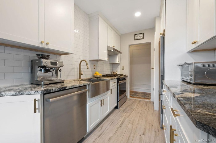 Stunning 17' eat-in-kitchen with granite counters, new high-end stainless steel appliances, custom white cabinetry, recessed lighting, a breakfast noo