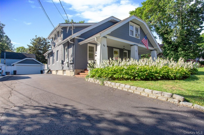 View of side of property with a detached garage, an outbuilding, stucco siding, and covered porch