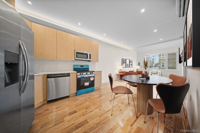 Kitchen with appliances with stainless steel finishes, light brown cabinetry, light wood finished floors, modern cabinets, and recessed lighting