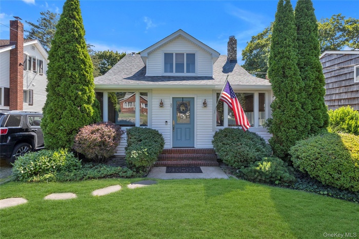 Expanded Cape-style house with roof with shingles, a chimney, and a front yard