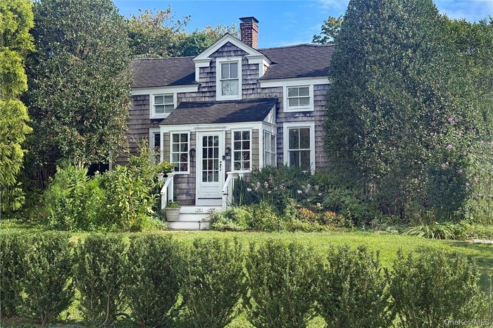 View of front of house with roof with shingles and a chimney