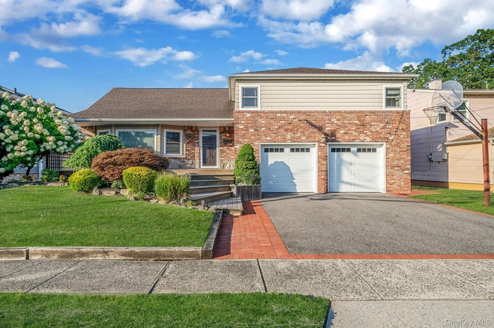 View of front of home with asphalt driveway, a garage, brick siding, and a front lawn