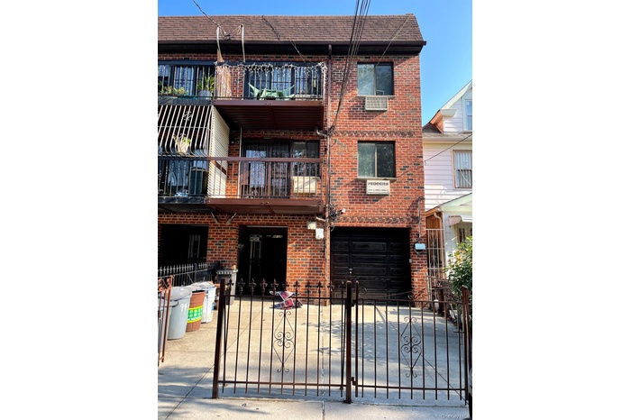 View of building exterior featuring a fenced front yard, a garage, and driveway