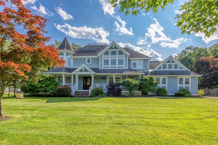 Victorian house with a porch, a front lawn, and roof with shingles