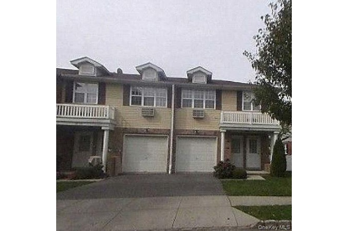 Colonial house with a balcony, driveway, and a garage