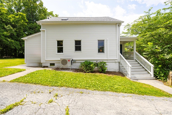 View of side of property with a yard, roof with shingles, and covered porch