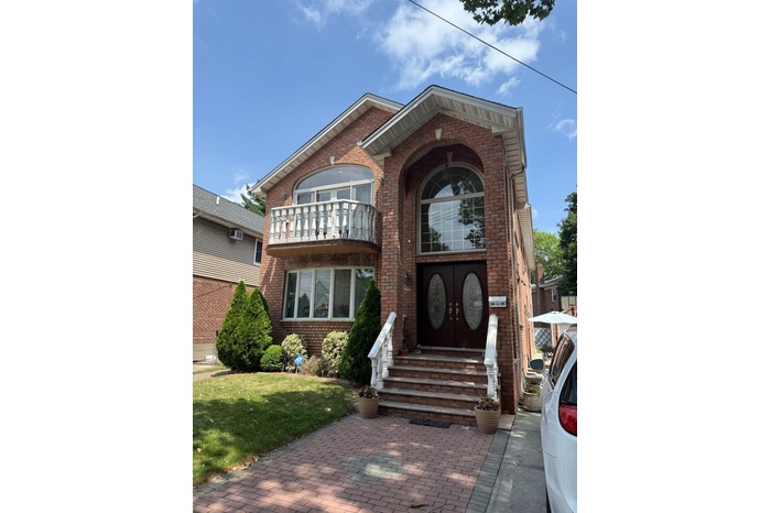 View of front of property with brick siding, entry steps, a front yard, and a balcony